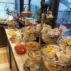 Un bufé con diversos alimentos, como frutas, quesos y pasteles.