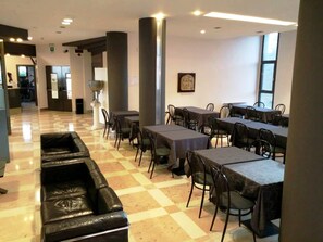 Un comedor amplio con suelo a cuadros, varias mesas con sillas y una columna central.