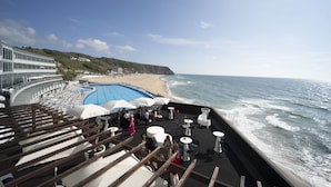 Een terras met buitenmeubilair met uitzicht op een strand en een zwembad.