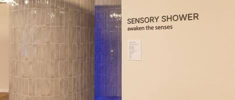 Ducha sensorial con un cartel que dice 'DUCHA SENSORIAL, despierta los sentidos'.