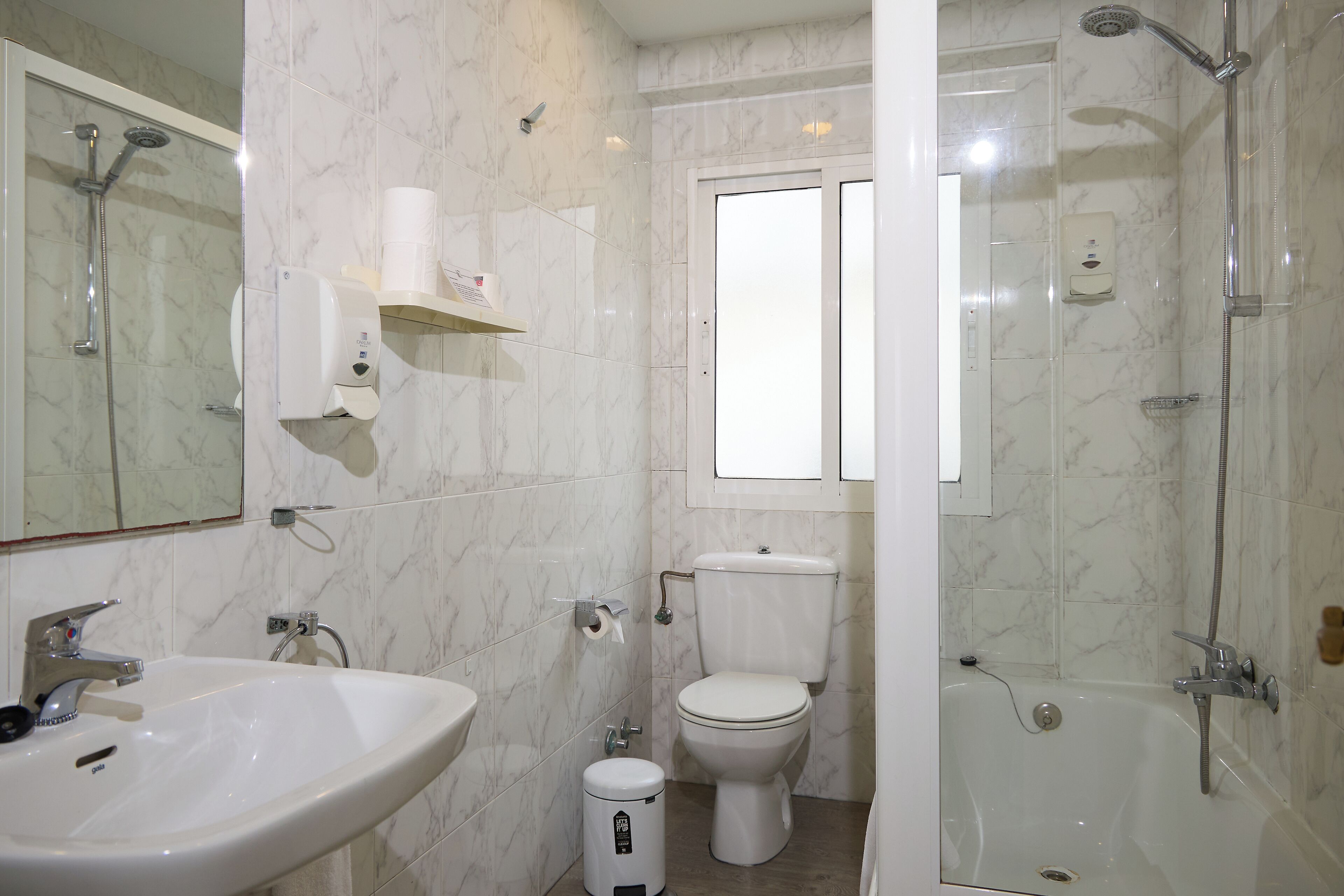 Un baño con lavamanos, inodoro y ducha.
