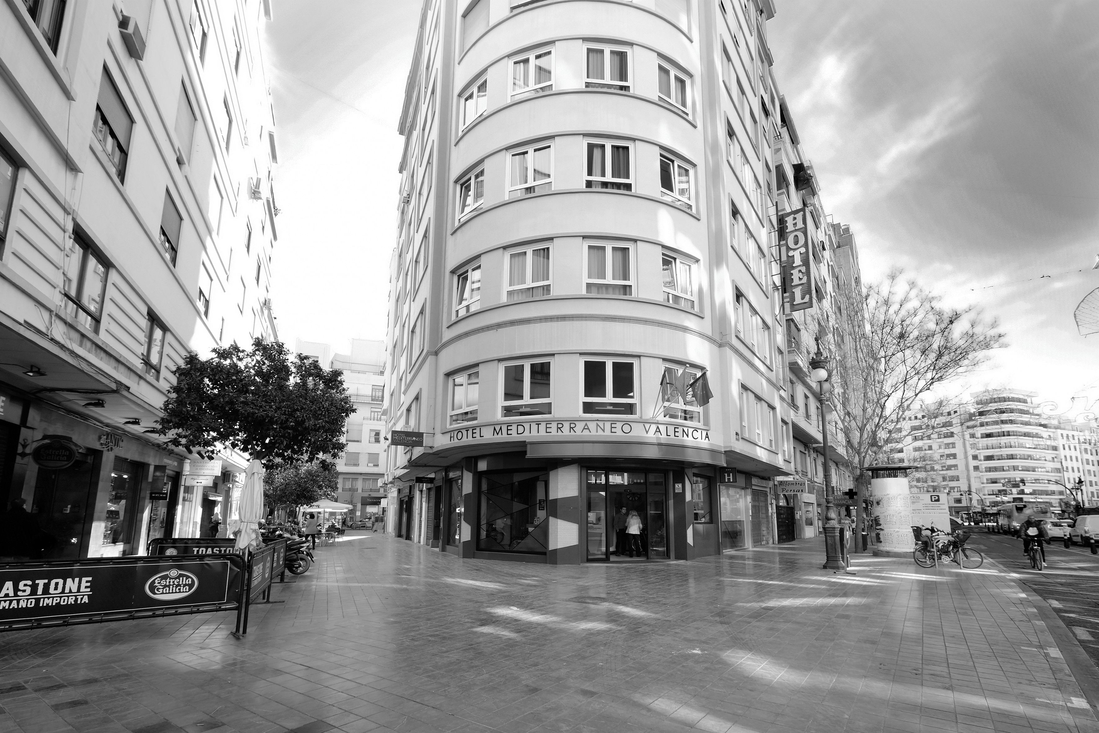 Ein mehrstöckiges Hotel mit einer geschwungenen Fassade, großen Fenstern und einem Schild, das es als Hotel Mediterraneo Valencia kennzeichnet.