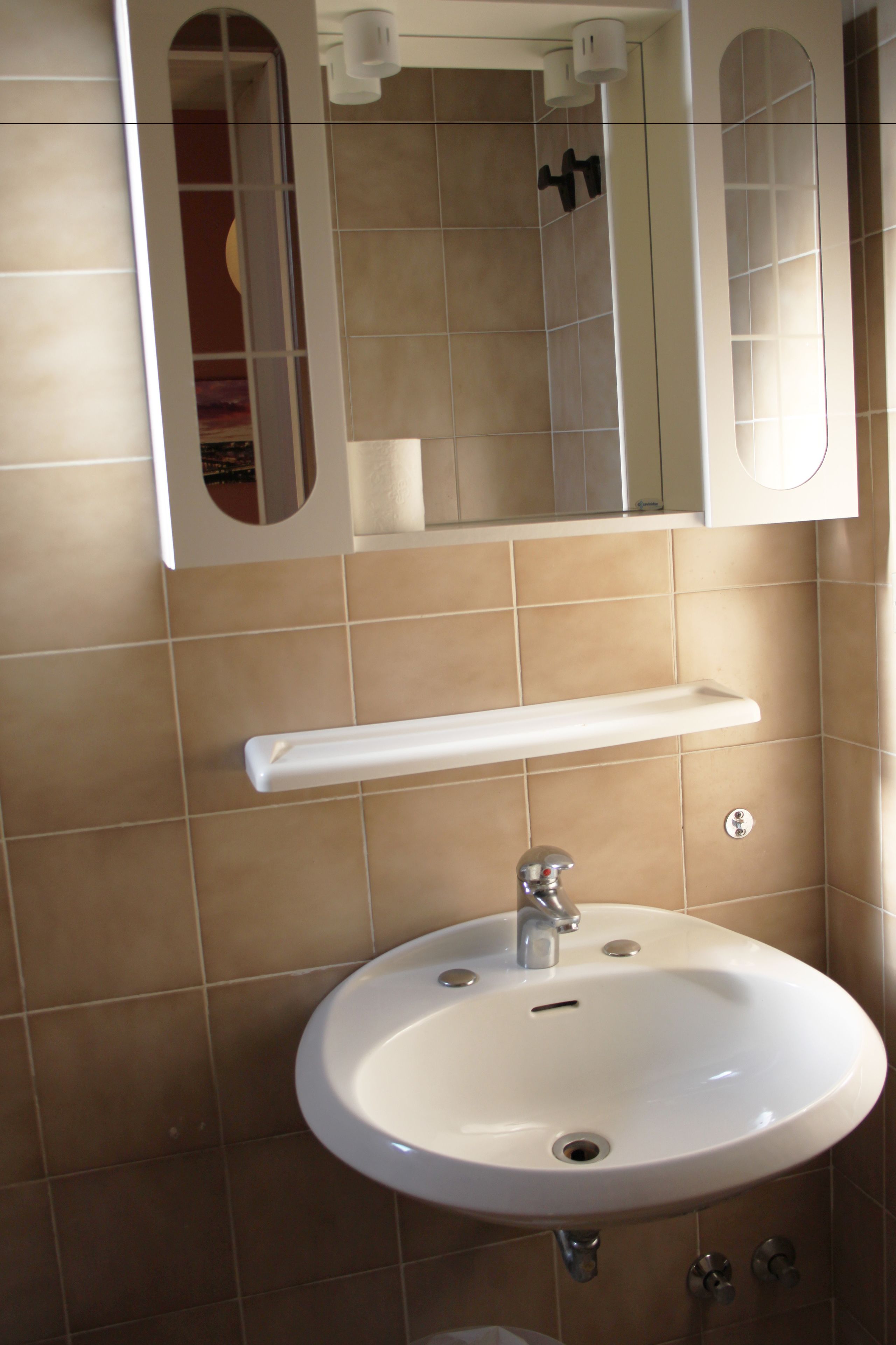 A bathroom with a white sink, a mirror, and a towel rack.