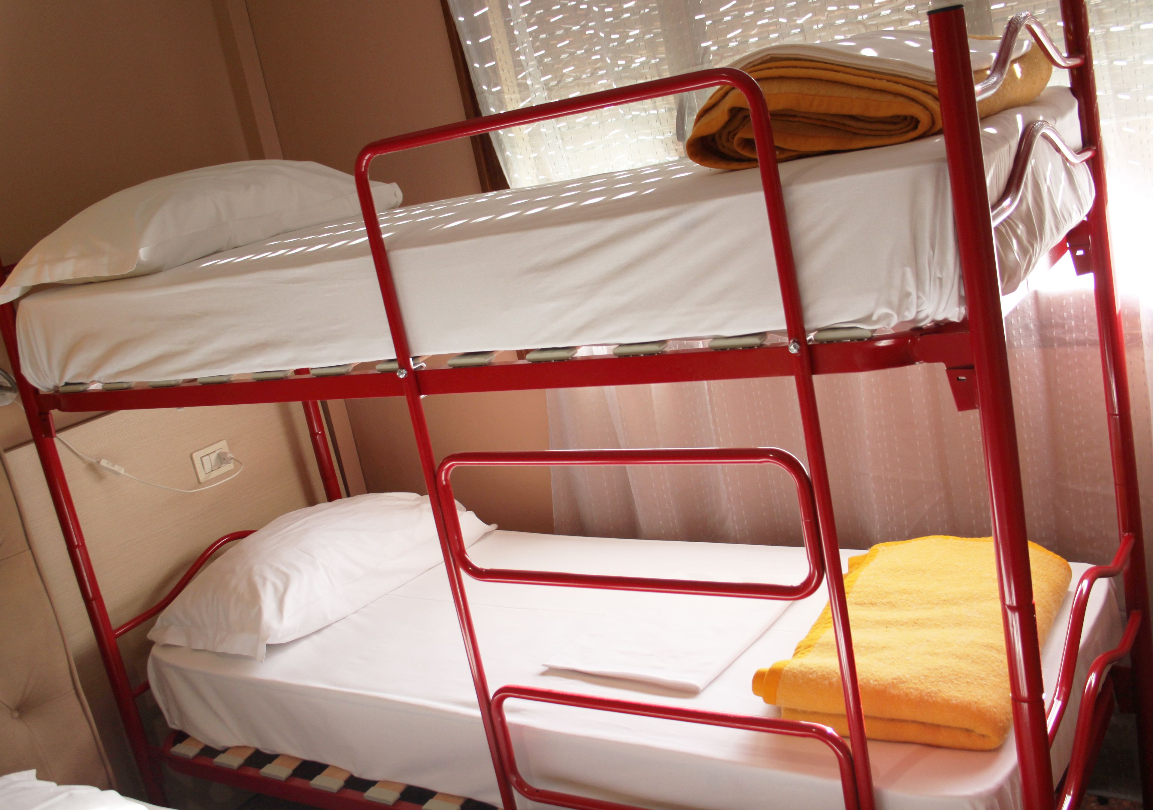 A bunk bed with two levels, each with a white mattress and pillows.