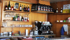 Una zona de bar con estantes llenos de botellas de licores, vasos y equipo para preparar café.
