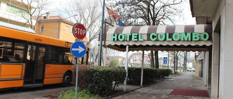 A hotel named HOTEL COLOMBO with a stop sign and directional sign nearby.
