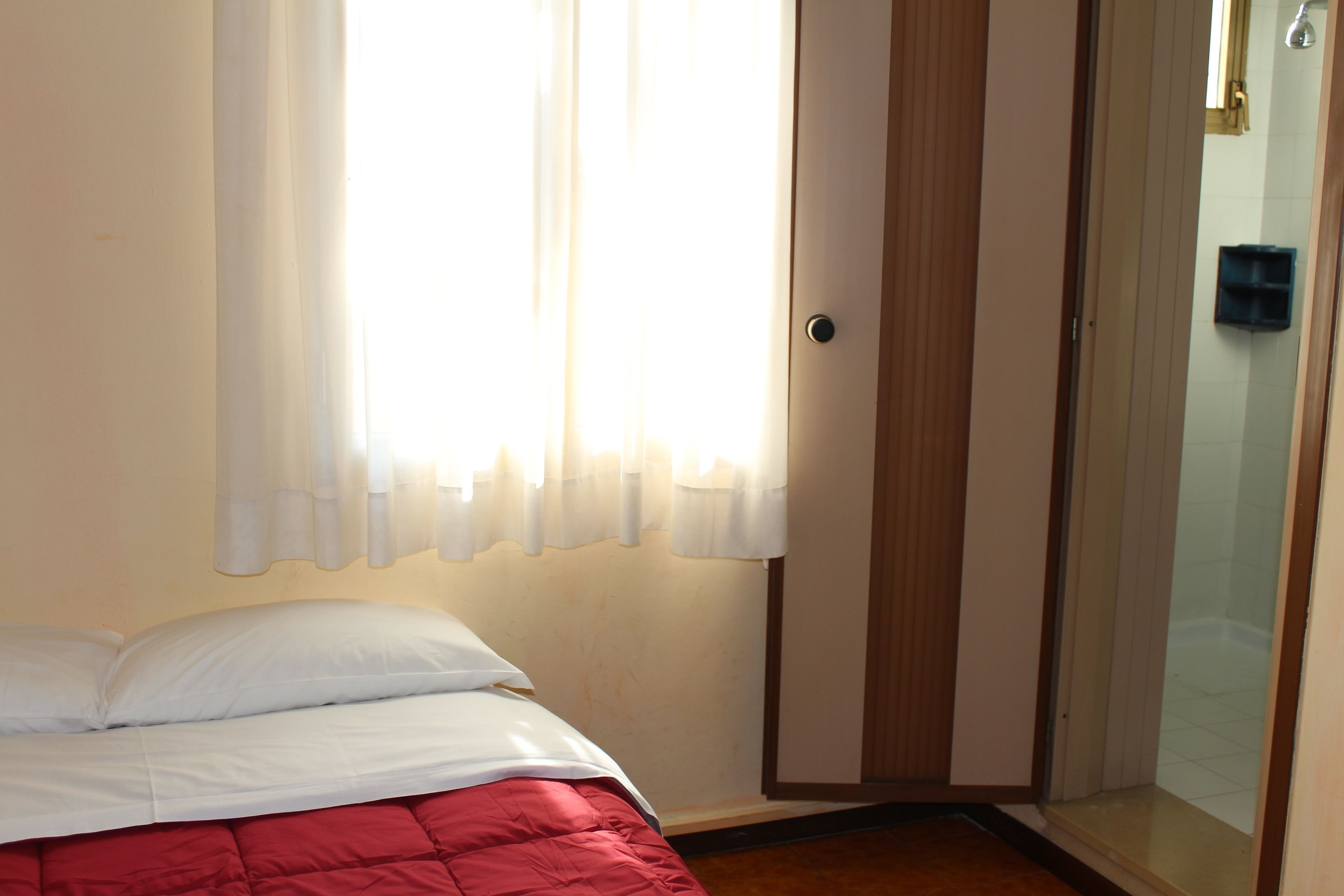 Ein Schlafzimmer mit Bett, einer Tür zum Badezimmer und einem Fenster mit Vorhängen.
