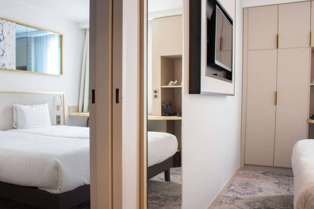 Une chambre d’hôtel comprenant un lit, un téléviseur fixé au mur, une armoire et un bureau avec une chaise.