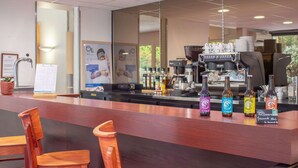 Zona de bar con mostrador, sillas y una máquina de café.