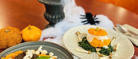 Una mesa de comedor con dos platos de comida, un florero decorativo y un adorno de telaraña.