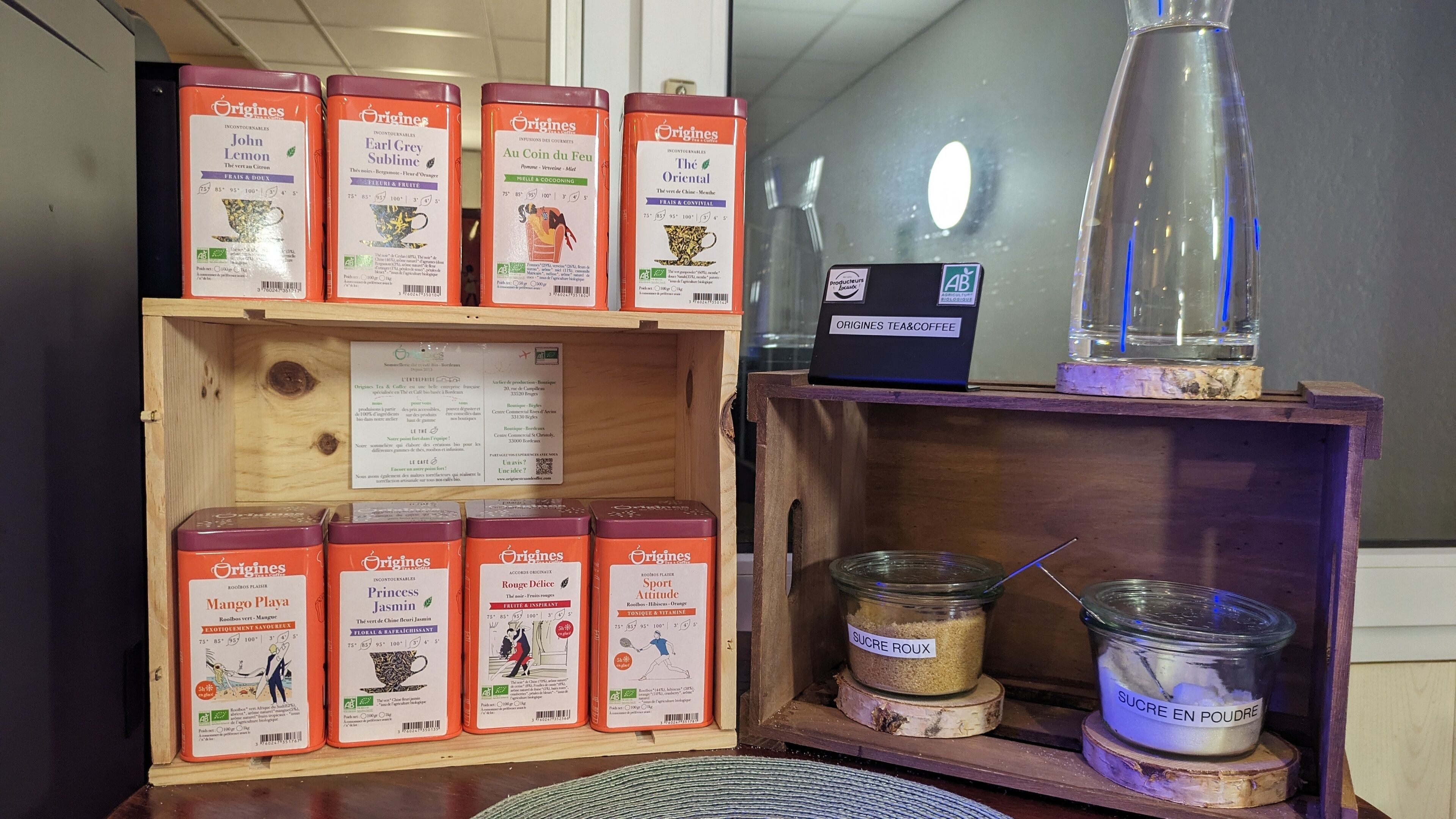 A display of tea and coffee products with a wooden box containing tea bags and a sign with product information.