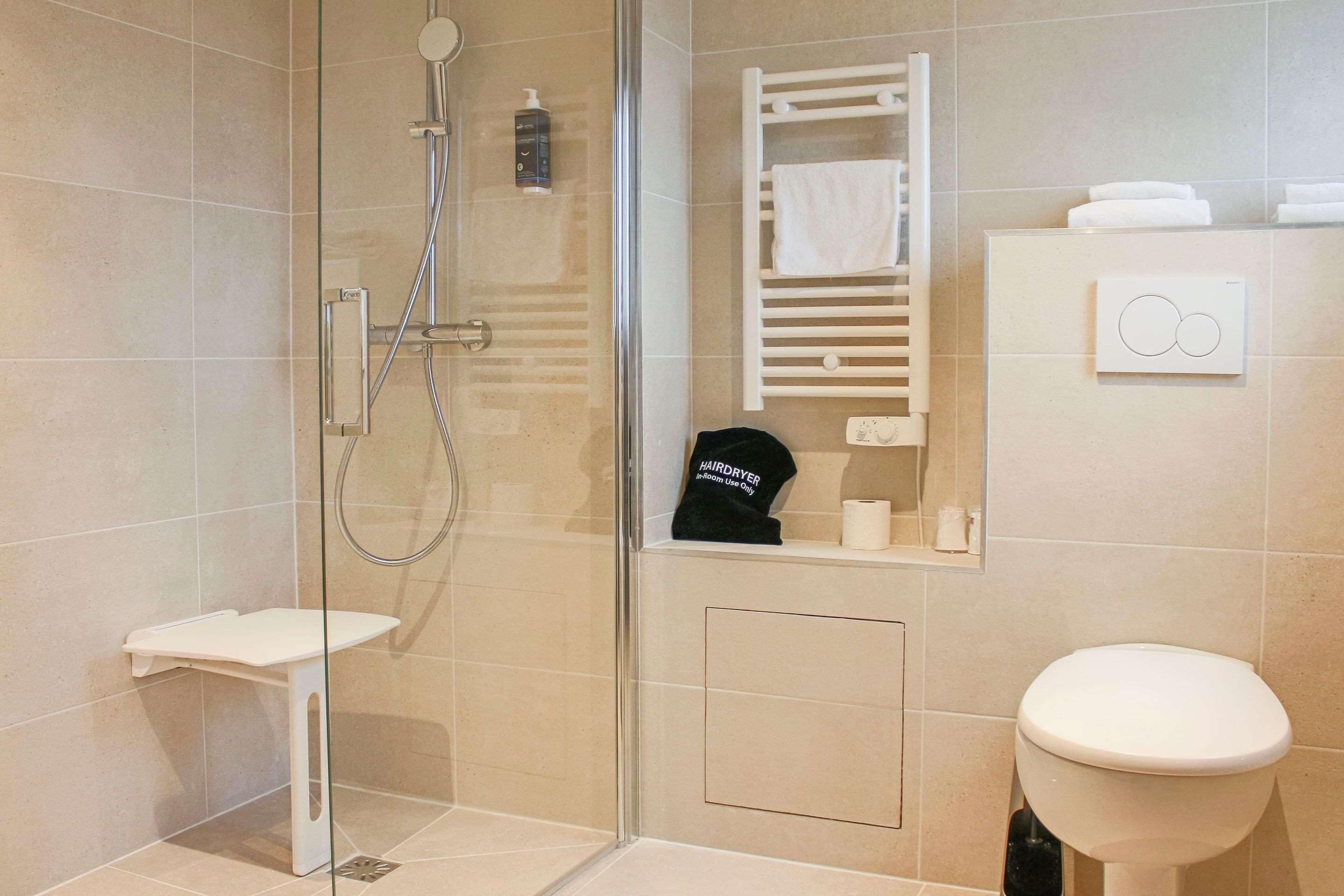 Une salle de bain moderne avec une douche à parois de verre, des toilettes blanches et un porte-serviettes.