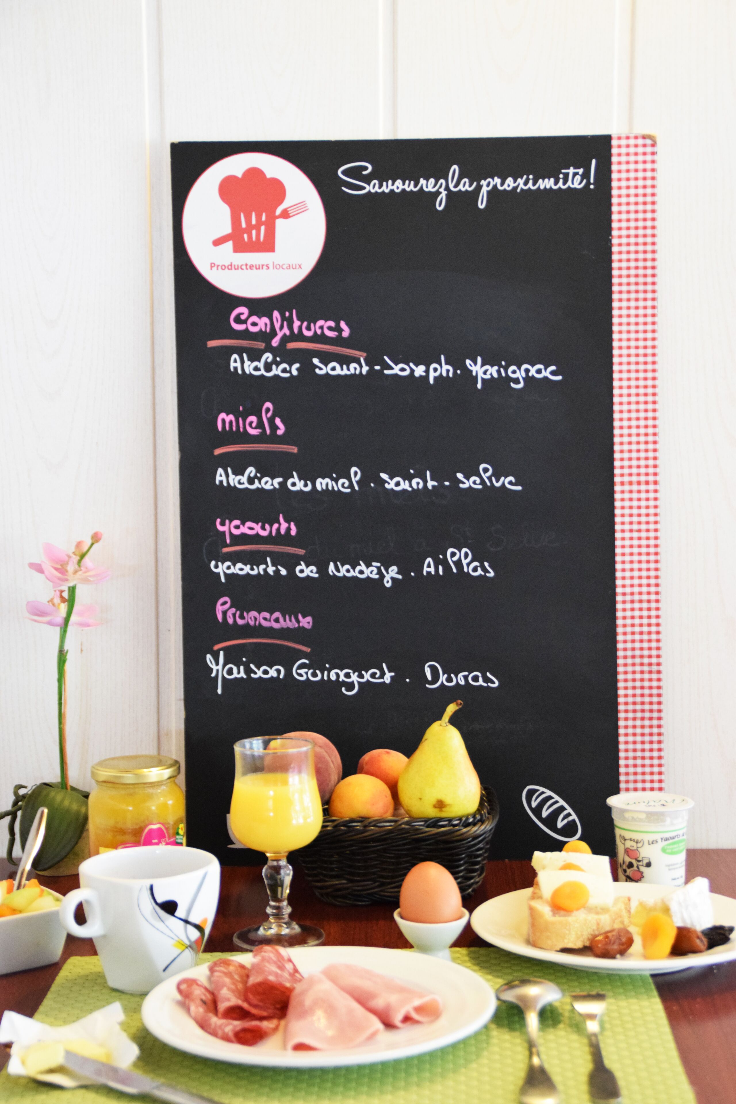 A breakfast setup with a menu board, fruits, and various breakfast items.