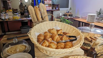 Een buffettafel met brood, croissants en een mandje gebak.