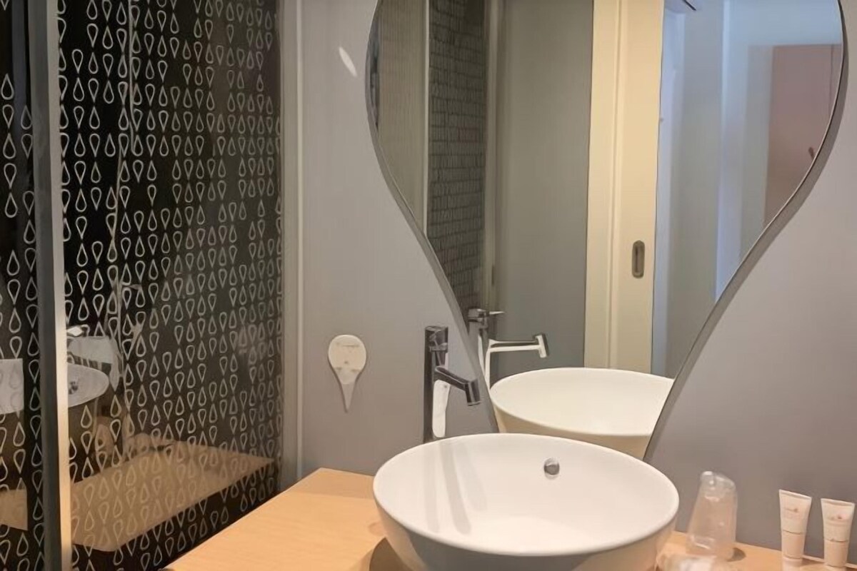 Ein Badezimmer mit großem Spiegel, Waschbecken und Duschbereich.