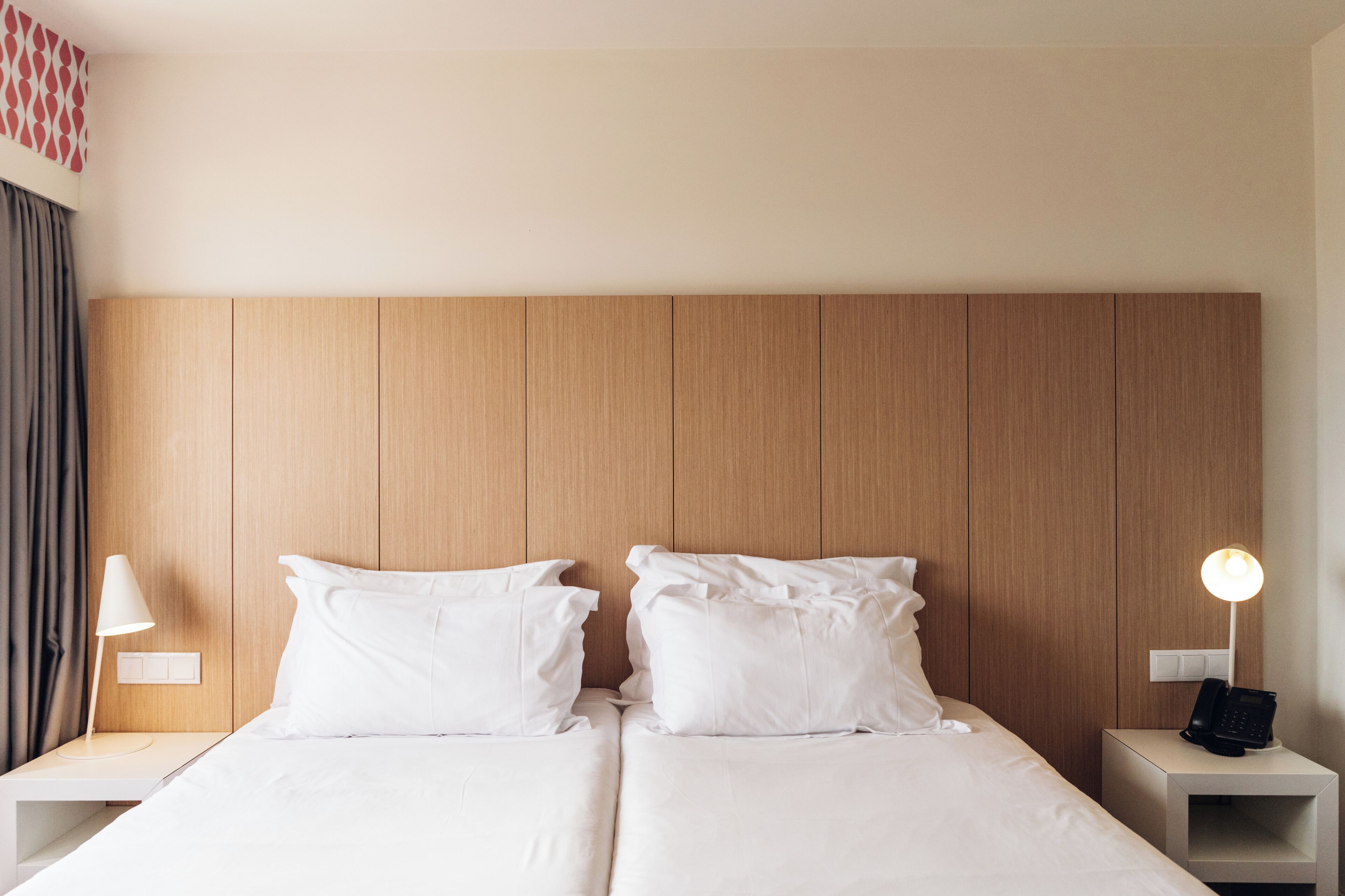 A double bed with white linens, two bedside tables with lamps, and a wooden headboard.