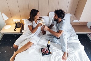 A couple sitting on a bed with a bottle of champagne and a bowl of grapes. - Stay Hotel Lisboa Centro Saldanha (Lisbon)