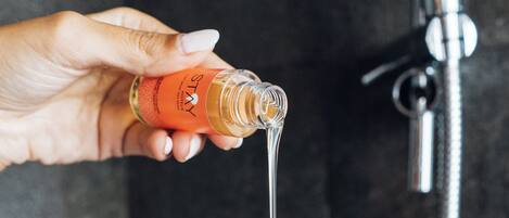 A hand holding a bottle with a liquid being poured into another hand.