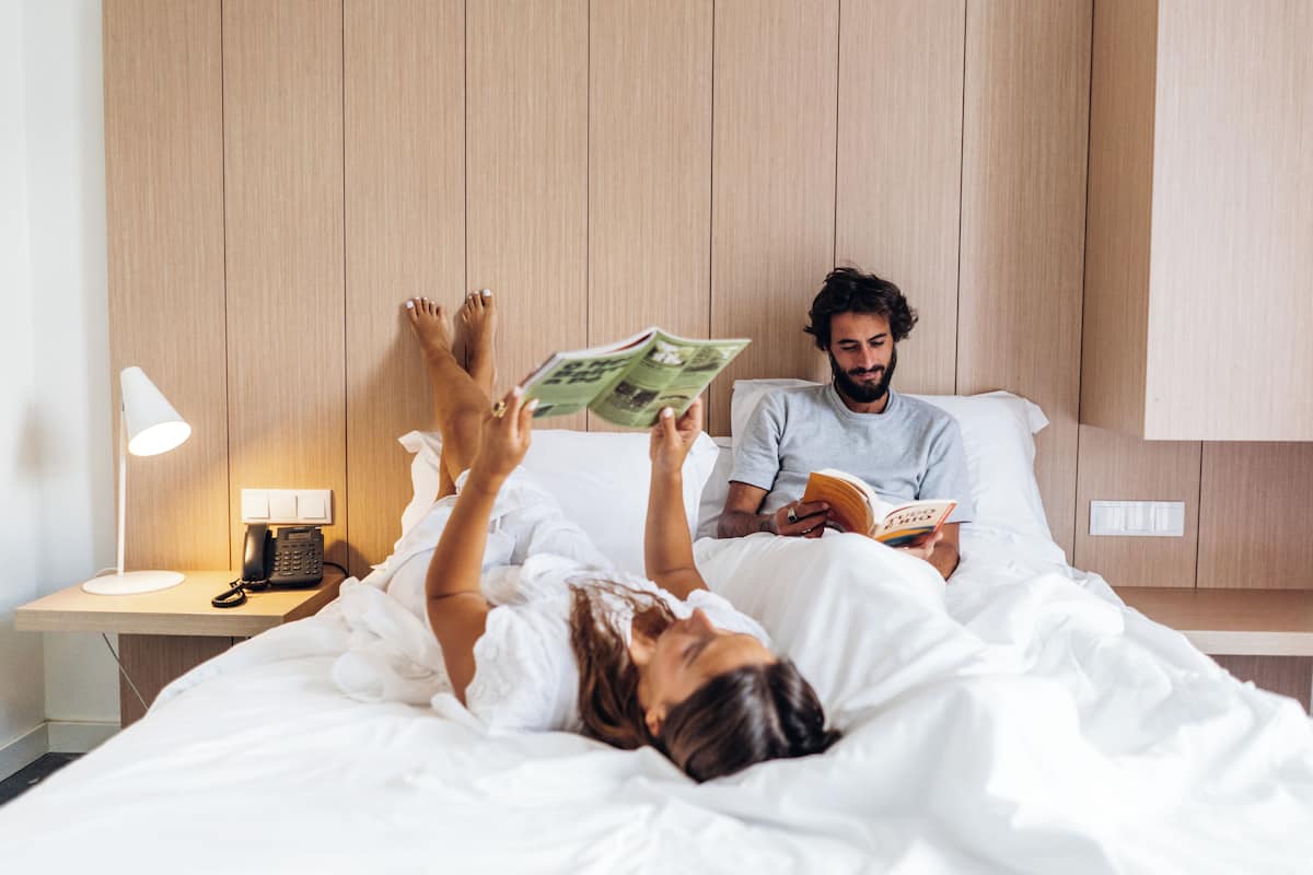 Un dormitorio con cabecera de madera, una mesita de noche con lámpara y un teléfono.