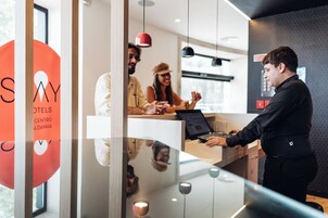 Modern dizájnú recepciós pult, üveg válaszfal és jól látható „SAY Hotels” logó.
