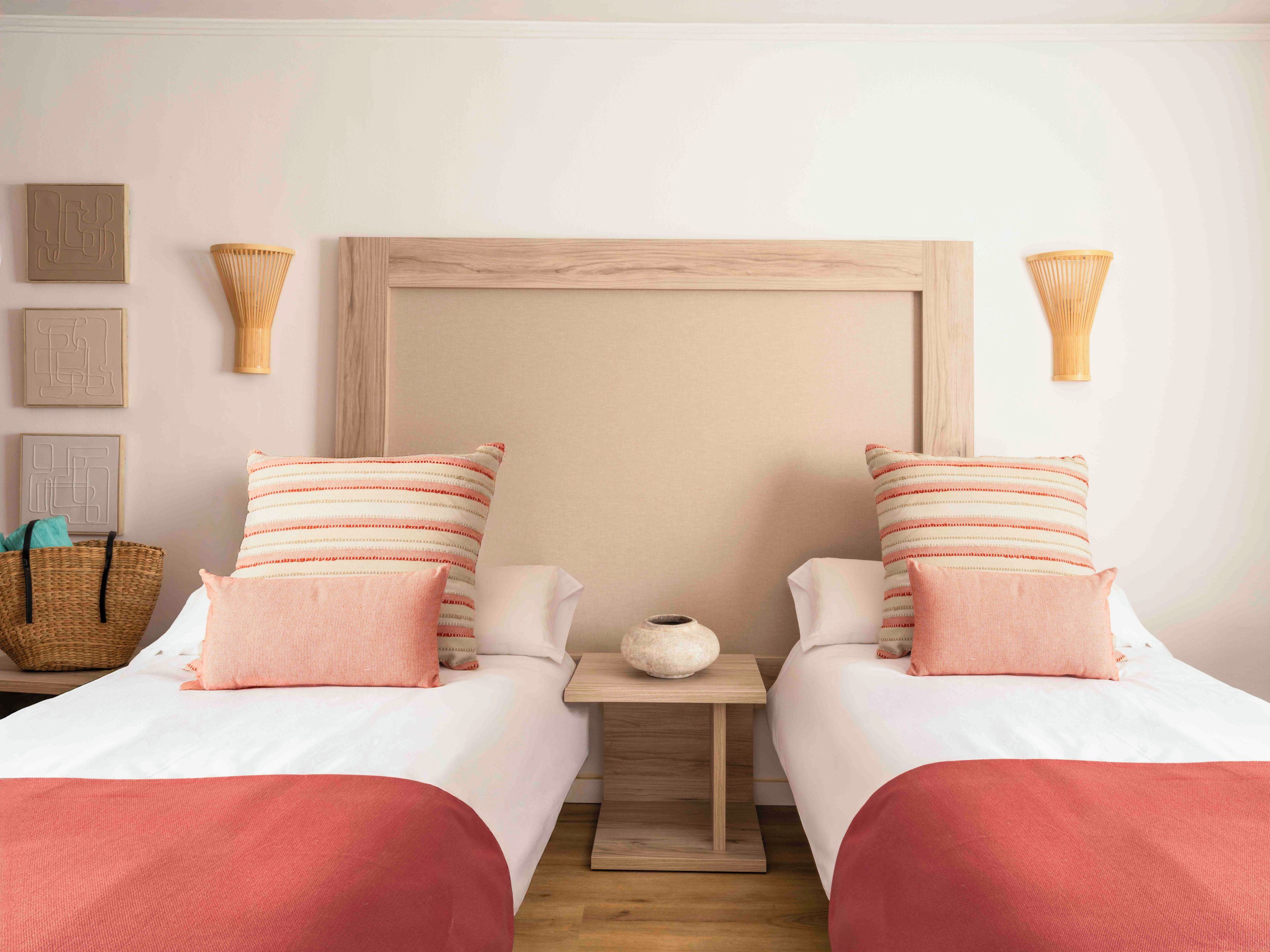 Un lit double avec une tête de lit en bois, deux tables de chevet, un panier en osier et un vase posé sur l’une des tables.