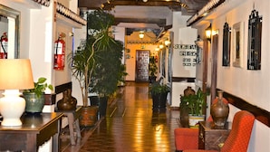 A hotel lobby with a polished tile floor, potted plants, a red armchair, and a sign reading "RESTAURANTE". - Ona Las Rampas (Fuengirola)