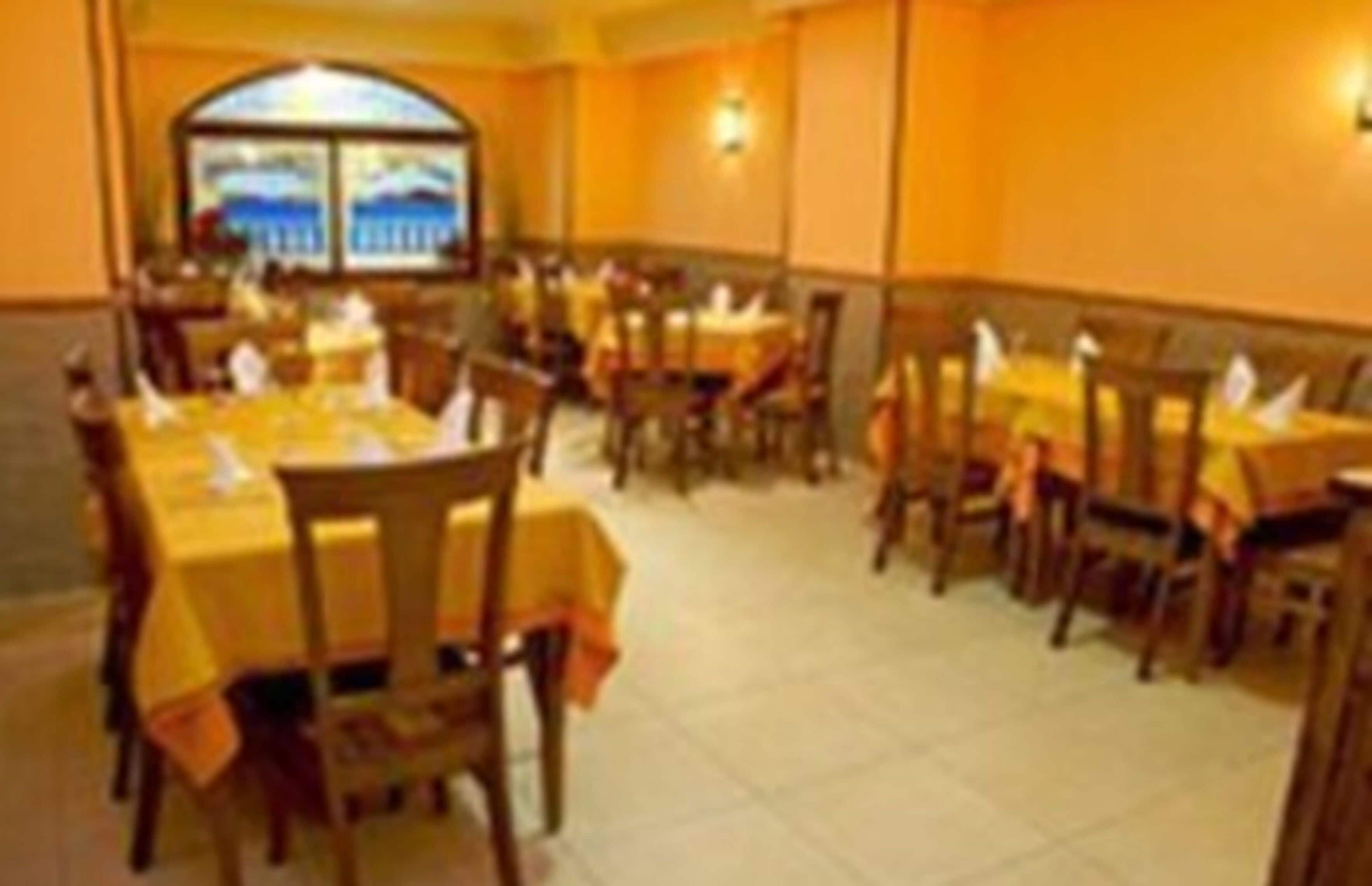 Een restaurant met verschillende tafels en stoelen, een betegelde vloer en een groot raam met uitzicht.