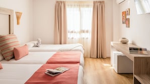 A hotel room with two beds, a desk, a small refrigerator, and a window with curtains. - Ona Las Rampas (Fuengirola)