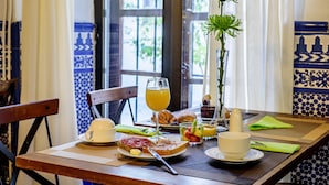 A breakfast table with croissants, toast, fruit, and a glass of orange juice.