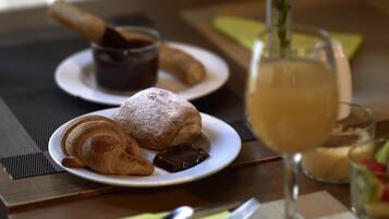 A table with croissants, a chocolate spread, and a glass of beverage.