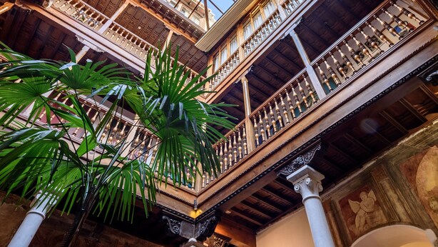 A spacious atrium with a high ceiling, ornate wooden balconies, and a central skylight. - Palacio de Santa Inés hotel (Granada)