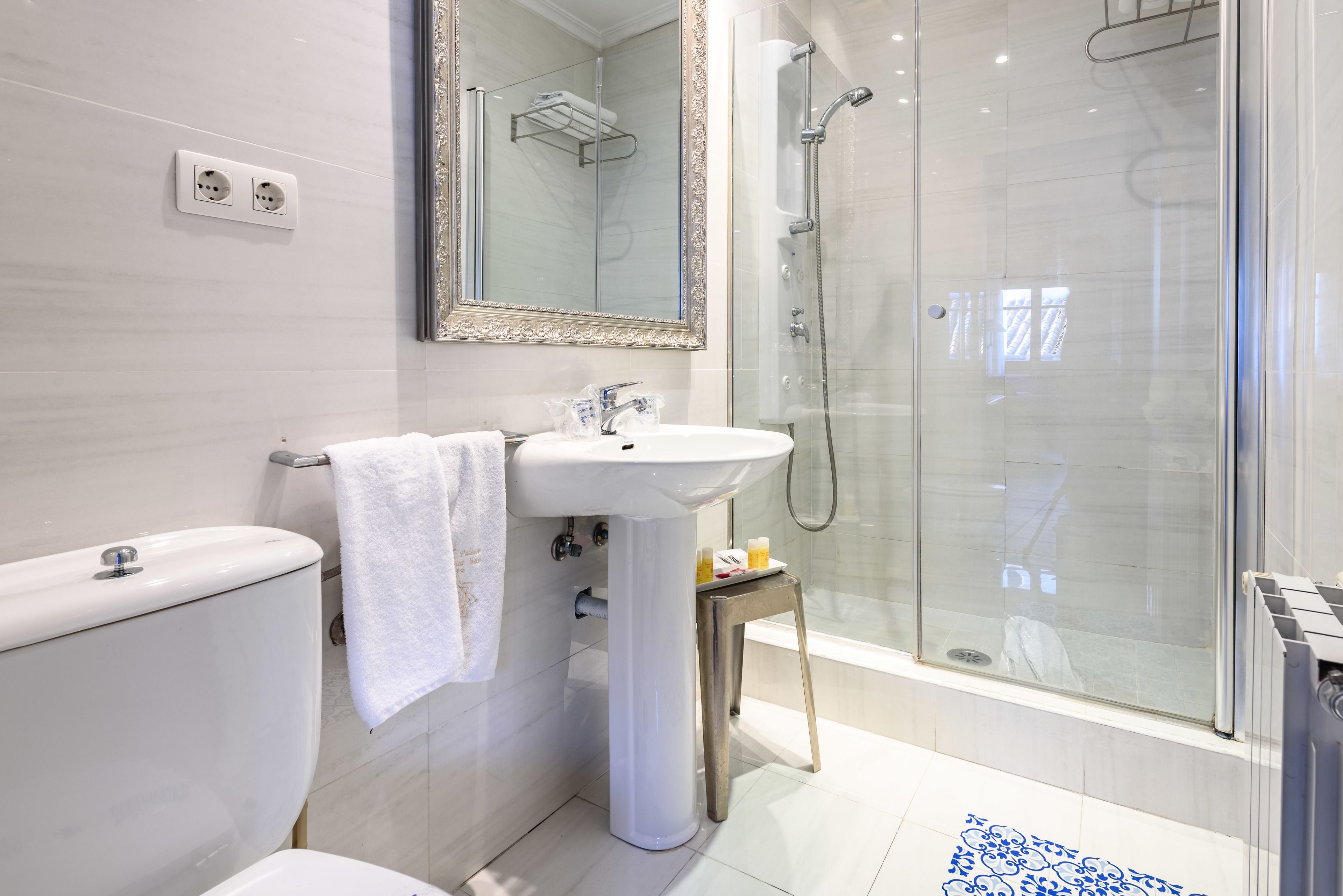 Un baño moderno con inodoro, lavamanos y ducha con mampara de vidrio.