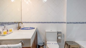 A bathroom with a white sink, a toilet, and a trash bin.