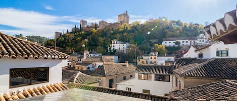 Un pueblo con arquitectura tradicional, que incluye tejados de tejas y un castillo destacado en una colina.