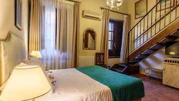 Habitación de hotel con cama, lámpara, espejo, escalera y radiador.