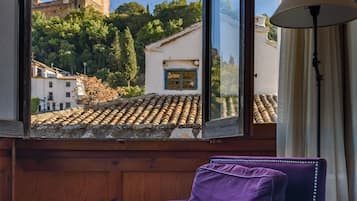 Une pièce avec vue sur une tour historique, un fauteuil violet et une table sur laquelle se trouve un plateau avec des tasses.