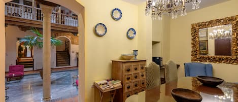 Un hall d’entrée spacieux, agrémenté d’un grand escalier, d’un lustre et d’un coin repas avec un grand miroir et des assiettes décoratives.