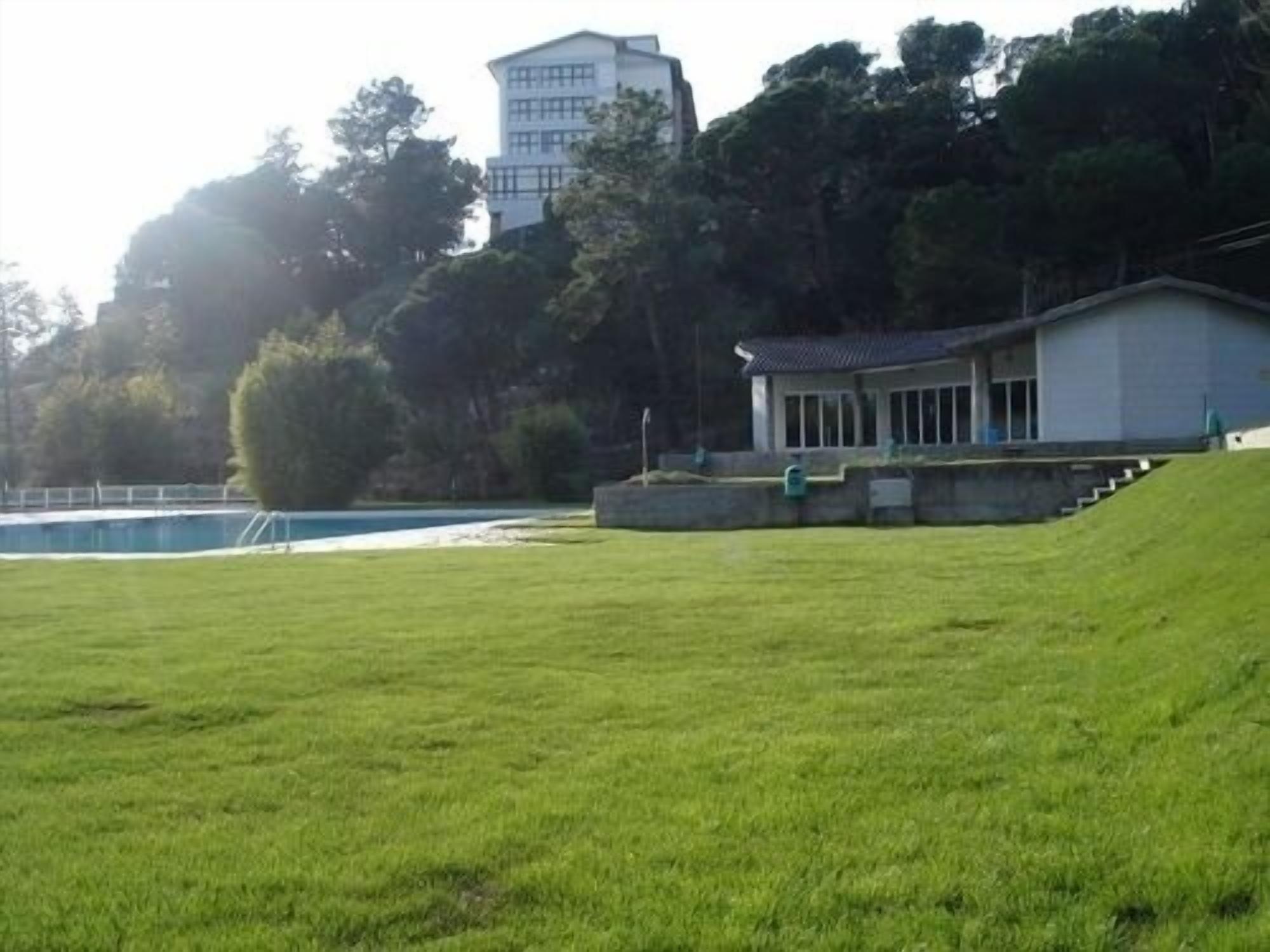 A grassy field with a building that has a traditional architectural style, possibly a house or a small structure.