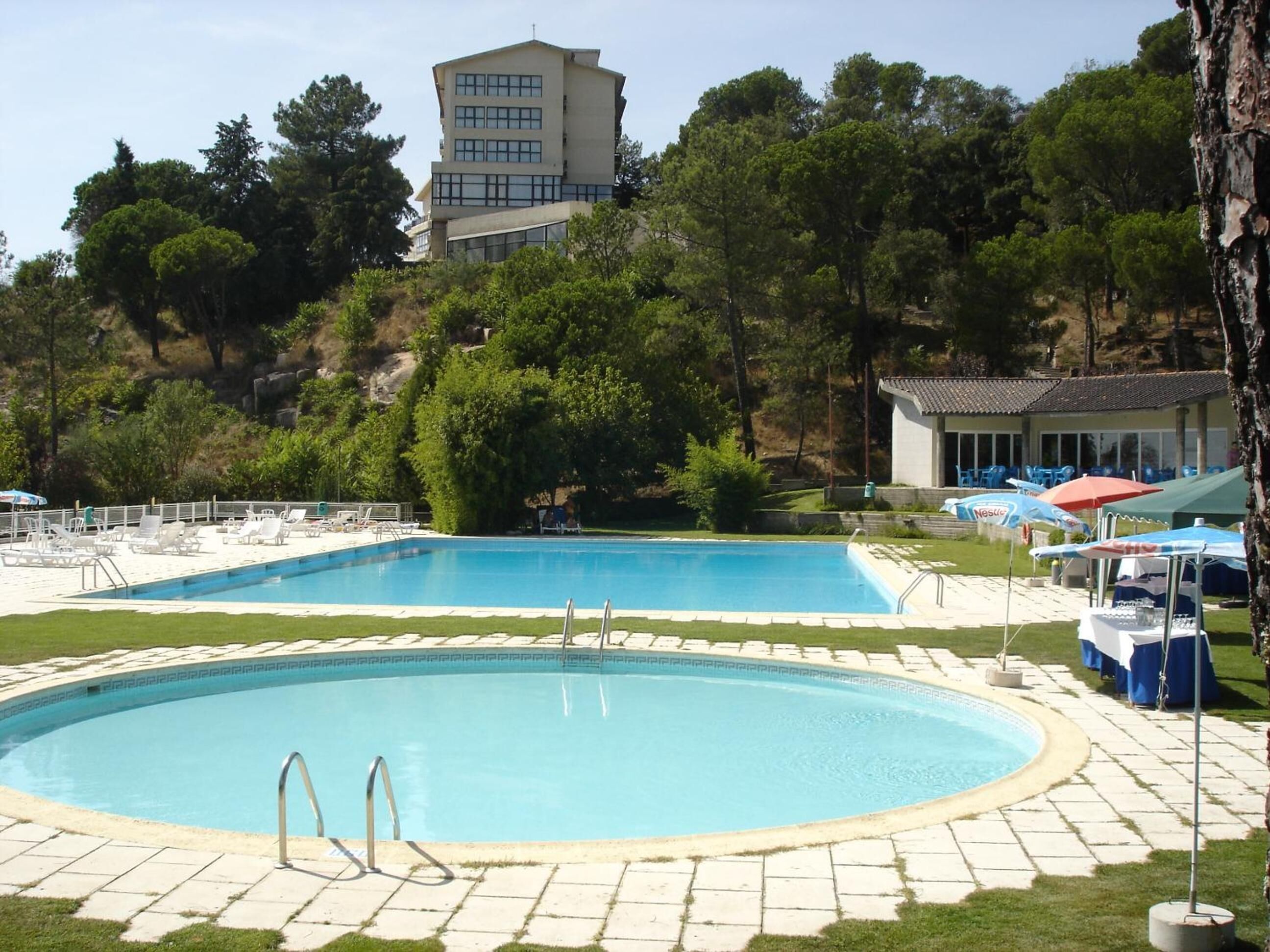 Una piscina techada, una piscina al aire libre de temporada, sombrillas