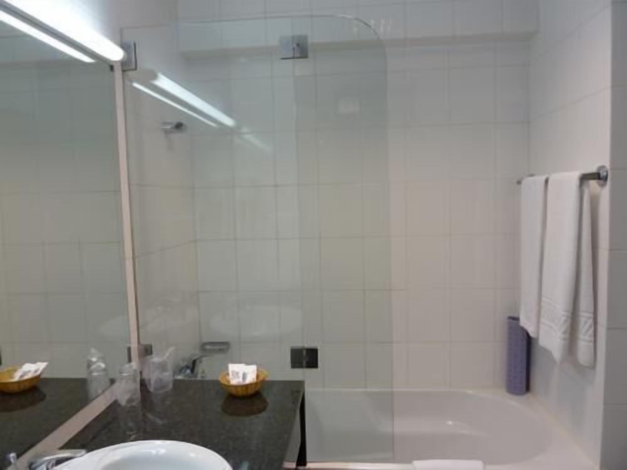 Un bany modern amb un plat de dutxa de vidre, un mirall gran i una banyera.