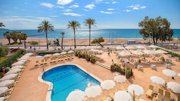 Una piscina al aire libre, sombrillas, tumbonas