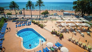 Una piscina al aire libre, sombrillas, sillones reclinables de piscina