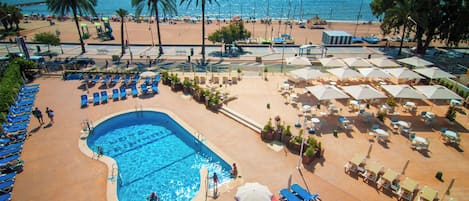 Una piscina al aire libre, sombrillas, sillones reclinables de piscina