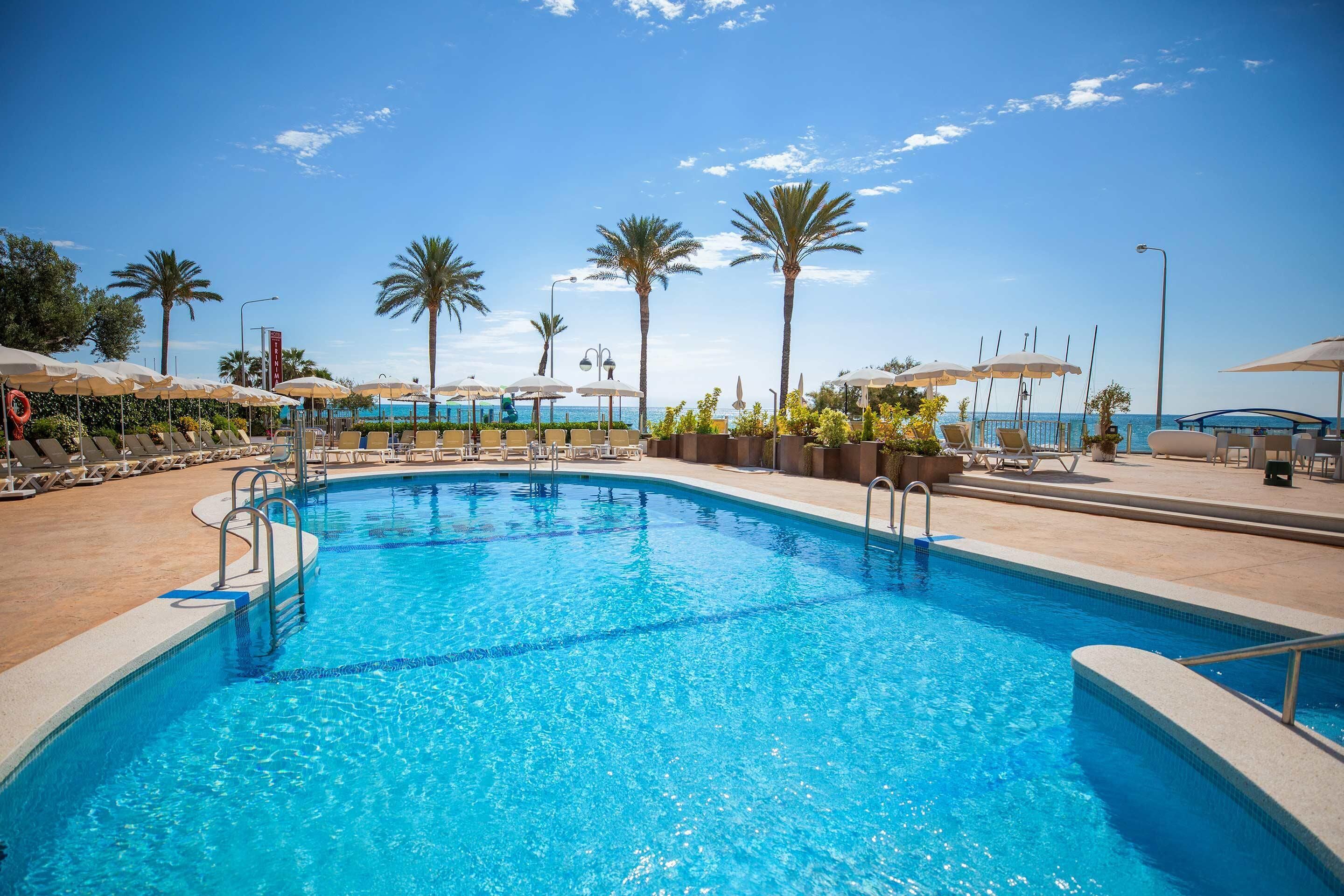 Una piscina al aire libre, sombrillas, tumbonas