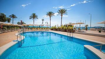 Una piscina al aire libre, sombrillas, tumbonas