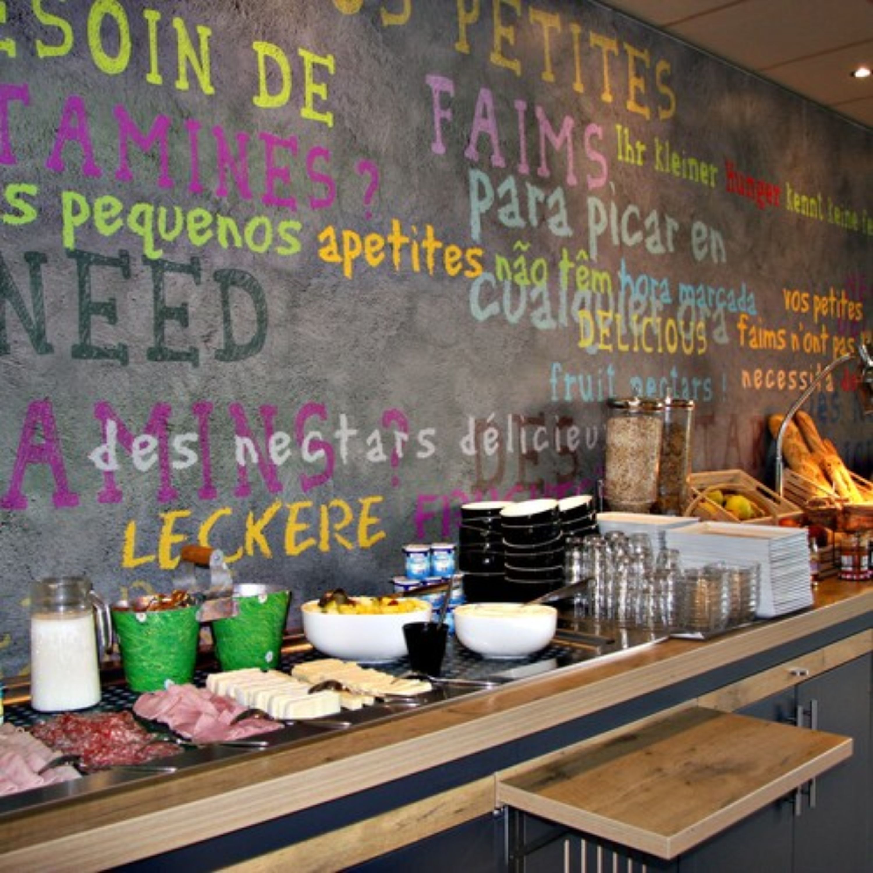 A breakfast buffet with various food items and a chalkboard with menu options in multiple languages.