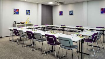 Une salle de conférence avec une longue table, des chaises et des ventilateurs de plafond.