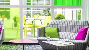 A modern interior with a grey sofa, a small table, and yellow chairs. - ibis Styles Antony Paris Sud (Antony)