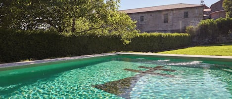 A clear swimming pool with a stone building in the background.