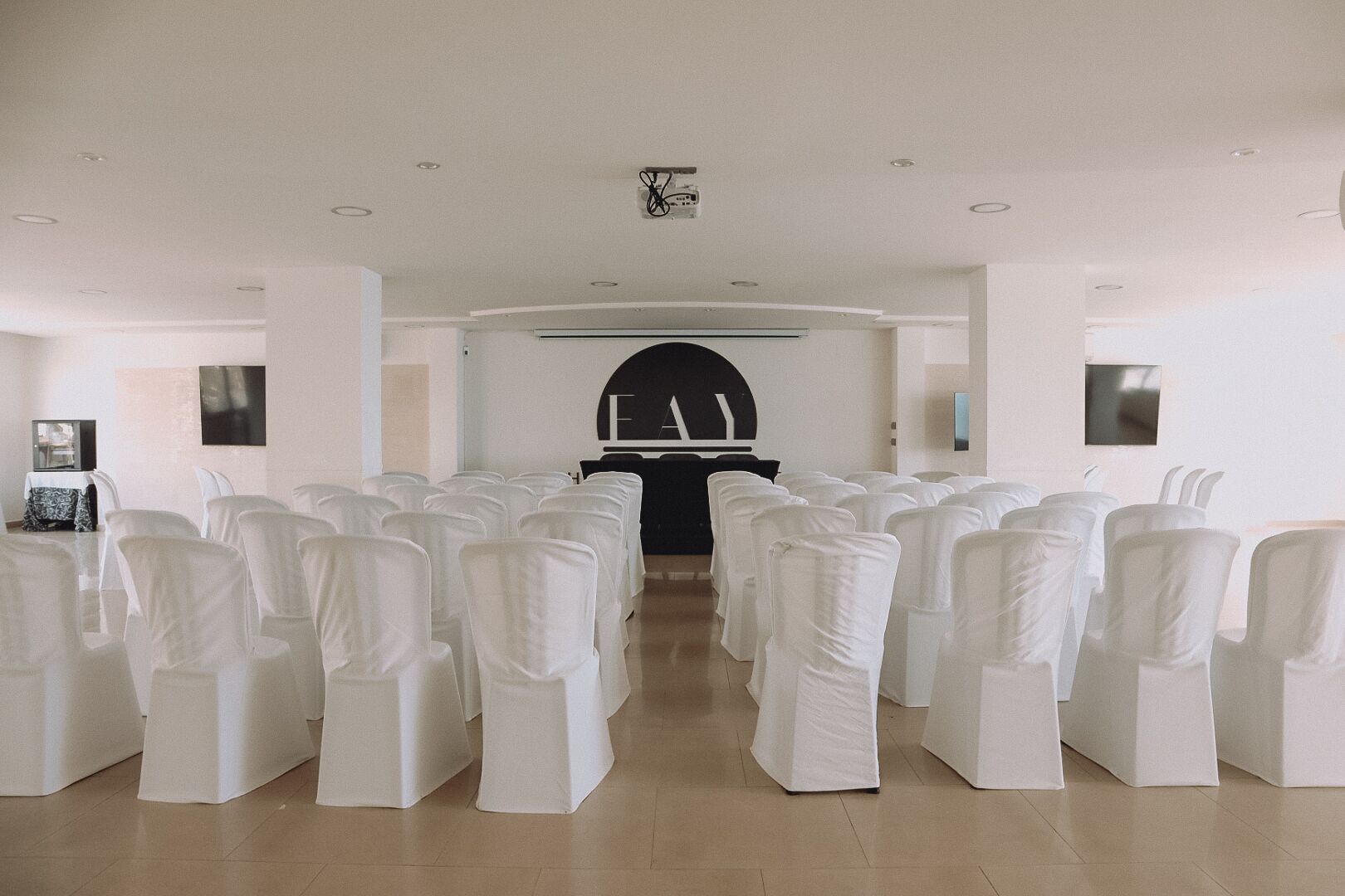 A conference room with rows of white chairs and a podium at the front.